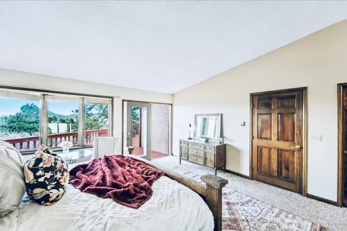 Master bedroom with mountain view through sliding glass door to deck