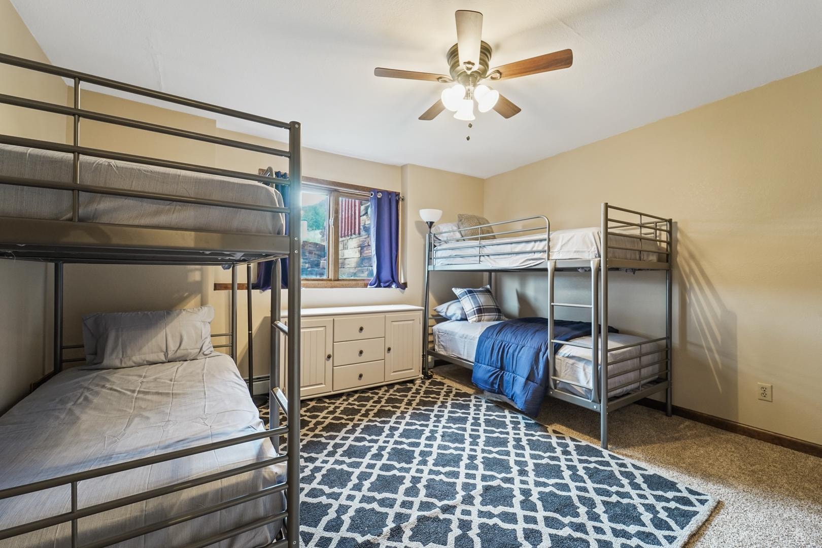 Bunk room with two sets of bunk beds and patterned rug